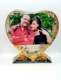 a heart shaped photo frame with a couple in the center and gold flakes around it