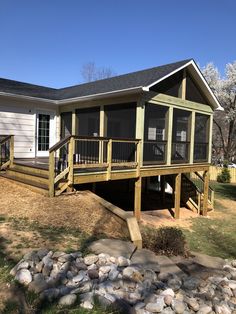 a house that has a deck on the side of it and rocks in front of it