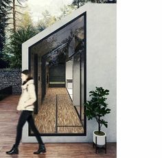 a woman walking past a white building on a wooden floor