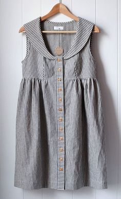 a black and white striped dress hanging on a wooden hanger next to a wall