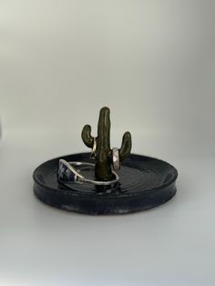 a small metal cactus sitting on top of a black plate