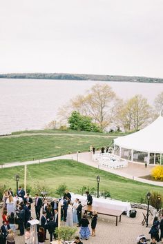 a group of people that are standing in front of a tent and some grass near the water