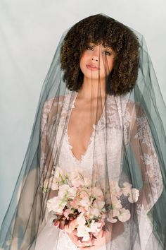 a woman wearing a veil holding a bouquet of flowers