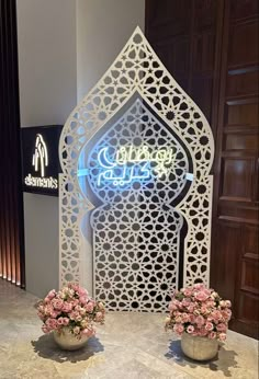 two vases filled with flowers sitting on top of a table next to a sign