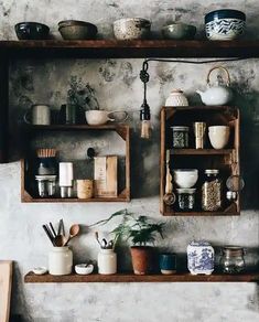 the shelves are filled with pots and pans on top of each other in front of a stone wall