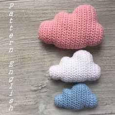 three crocheted clouds sitting on top of a wooden table