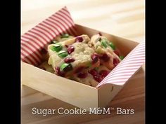 sugar cookie m & m bars in a red and white box on a wooden table