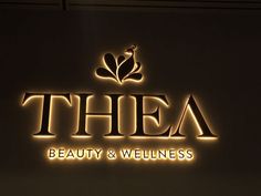 thea beauty and well - being logo is lit up in front of a wall