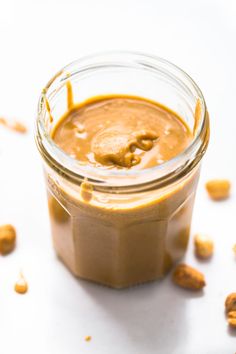 peanut butter in a glass jar with peanuts scattered around it and the words homemade peanut butter in 5 minutes