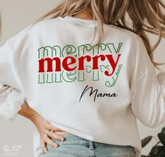 a woman wearing a merry sweatshirt with the words mama printed on her back in red, green and white