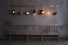 a wooden bench sitting in front of a wall with hanging lights on it's sides