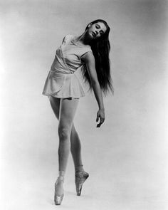 a black and white photo of a woman in ballet attire with long hair, dancing