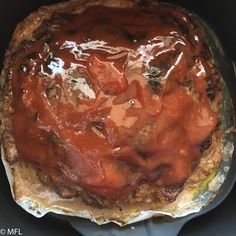 a meat pie with sauce on top in a pan, ready to be baked or eaten