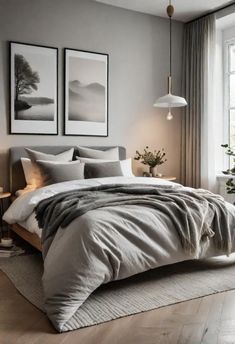 a bedroom with grey walls and white bedding, two pictures on the wall above the bed