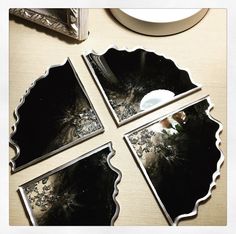 four black and white plates sitting on top of a table next to a plate with silver trim