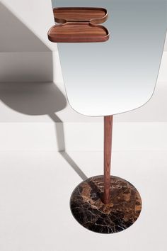 a mirror sitting on top of a table next to a wooden stand with a piece of wood sticking out of it