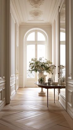 an empty hallway with vases and flowers on the table