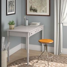 a small desk with a stool in front of it and a map on the wall