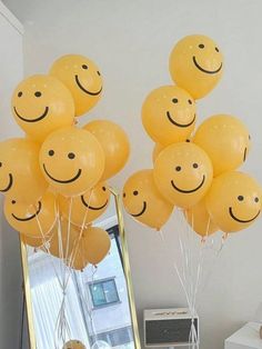 a bunch of balloons that have been placed in front of a mirror with smiley faces on them