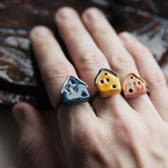 three different colored dice shaped rings on someone's hand