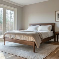 a bedroom with a bed, nightstands and windows in the room that has wood flooring