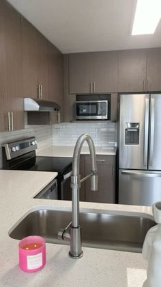 a kitchen with stainless steel appliances and white counter tops, including a sink that has a faucet in it