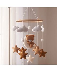 a teddy bear is sitting on the moon and stars mobile