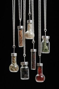 several glass bottles filled with different types of items hanging from chains on a black background