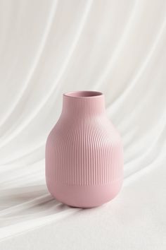 a pink vase sitting on top of a white sheet