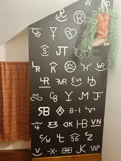 a blackboard with letters and numbers written on it next to a wooden shelf in front of a curtain