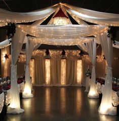 an indoor wedding venue with white drapes and lights