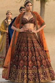 a woman in a brown and orange bridal gown standing next to two other women