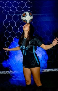 a woman is playing with a soccer ball on her head in front of a blue background