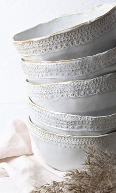 a stack of white bowls sitting on top of a table next to a pile of feathers