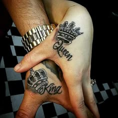 two people holding hands with tattoos on their fingers and the words queen and king written in cursive font