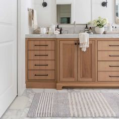 a bathroom with two sinks, mirrors and rugs on the floor in front of it