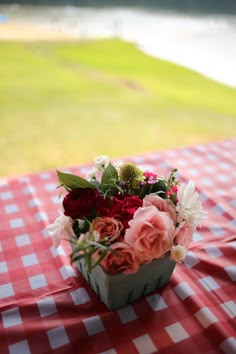 a flower arrangement sitting on top of a red and white checkered picnic table cloth