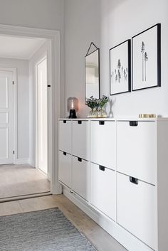 a white cabinet with drawers and pictures on the wall next to it in a living room