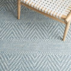 a wooden bench sitting on top of a blue and white carpeted floor next to a chair