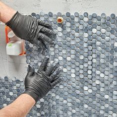 a man in black gloves and rubber gloves on a tile floor