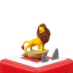 a lion figurine sitting on top of a red box next to a shark