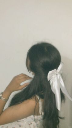 a woman with her back to the camera, wearing a white bow in her hair