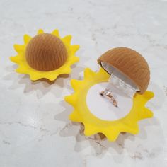 two rings are sitting on top of fake sunflowers and one has a ring in it's shell