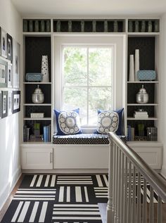 a window seat in the corner of a room with bookshelves and pictures on the wall