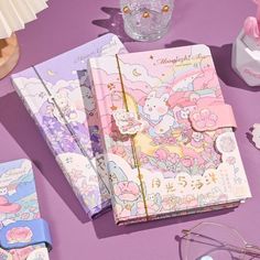 various stationery items are laid out on a purple surface with glasses and other accessories