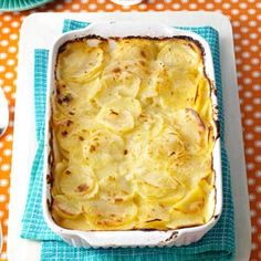 a casserole dish with potatoes in it on a blue and white napkin next to a fork