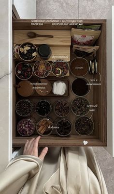 a person holding up a wooden box filled with spices and condiments in it