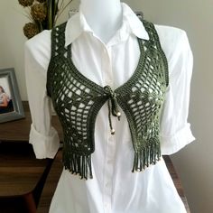 a white shirt with green crochet and tassels on the neckline