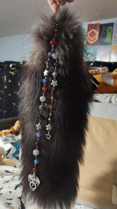 a person is holding up a long beaded necklace with beads and charms on it