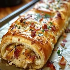 a long piece of bread with bacon and cheese on it sitting on a plate next to a knife